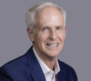 John Burns, CEO of John Burns Real Estate Consulting, smiles in a blue suit.